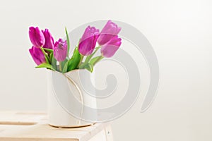 Beautiful Fresh Spring lila Tulips in Vase on bright background. photo