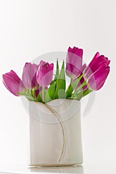 Beautiful Fresh Spring lila Tulips in Vase on bright background. photo