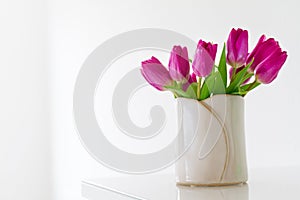 Beautiful Fresh Spring lila Tulips in Vase on bright background. photo