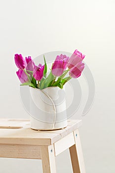 Beautiful Fresh Spring lila Tulips in Vase on Wooden Stool. Spri photo