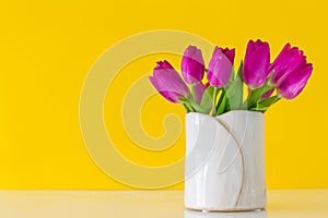 Beautiful Fresh Spring lila Tulips in Vase on yellow Background. photo