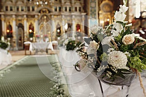 Beautiful fresh white flowers bouquet decoration for wedding ceremony in christian orthodox church, interior closeup