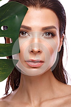 Beautiful fresh woman with perfect skin, natural make up and green leaves. Beauty face.