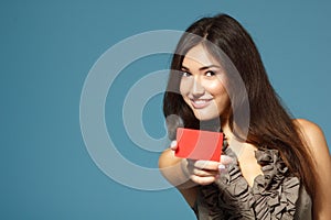 Beautiful friendly confident girl showing red card in hand, over