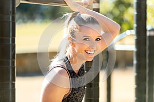 Beautiful friendly happy and smiling female exercising in the park at pull up bar outdoor gym