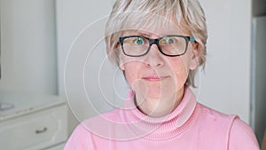 Beautiful friendly middle aged adult woman wearing glasses smiling and looking at camera indoors.Close up portrait of face