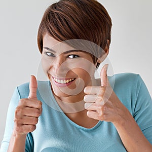Beautiful, friendly, smiling woman giving two thumbs up