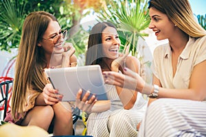 Beautiful friends in a cafe using digital tablet and having fun