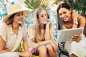 Beautiful friends in a cafe using digital tablet and having fun