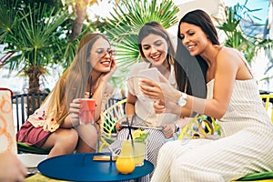 Beautiful friends in a cafe using phone and having fun