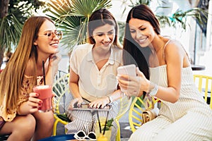 Beautiful friends in a cafe using phone and having fun