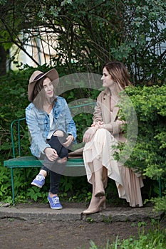Beautiful friends talking and sitting on a park bench outdoors