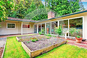 Beautiful front yard landscape with vegetable garden and red tile walkway.