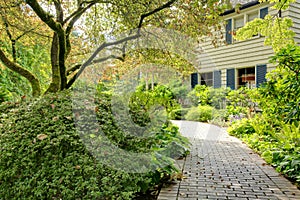 Beautiful front yard with walkway and grey brown large house.