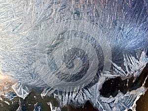 Beautiful frostwork on a window glass as an abstract winter background blue white ice stripes, frost pattern