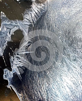 Beautiful frostwork on a window glass as an abstract winter background blue white ice stripes, frost pattern