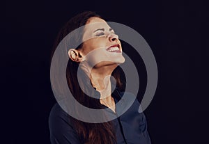 Beautiful funny toothy laughing business woman with folded arms in blue shirt on black background with empty copy space for text.