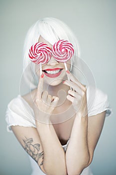 Beautiful funny woman in white and perfect pink makeup holding two swirl lollipops