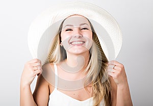Beautiful funny young blonde woman in white tank top and a large white hat smiling