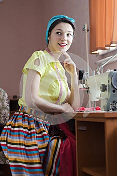 Beautiful funny young pinup woman in light green with sewing machine