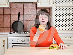 Hermoso ridículo mujer joven comer francés pan una hoja circular grande de masa ligera a hamburguesa 