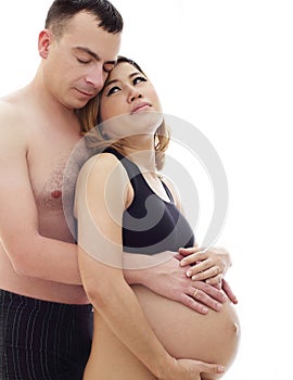 Beautiful future parents: his pregnant asian wife and a happy husband acting hug together