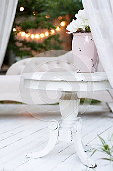 Beautiful garden vase with white roses and other flowers on the table, exterior, gazebo decor idea.