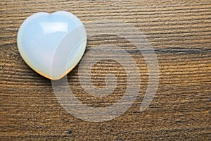 Beautiful gem stone heart on brown wooden background. Love and passion concept. Copy space
