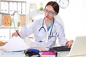 Beautiful general practitioner is working with joy. She is standing with a folder of documents in her hand