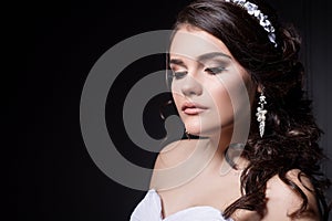 Beautiful gentle girl portraits of the bride in a white wedding dress with evening hairstyle with a rim of flowers in her hair and
