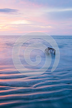 Beautiful gently waves, texture ripple marks, and traditional fish trap in surf. Thailand. Long exposure. Fantastic sunset sky and