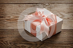 Beautiful gift box with a bow on the table from the old boards