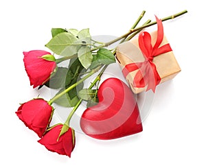Beautiful gift box, roses and red heart on white background, top view. Valentine`s day celebration