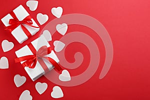 Beautiful gift boxes, hearts on red background, flat lay with space for text. Valentine`s day celebration