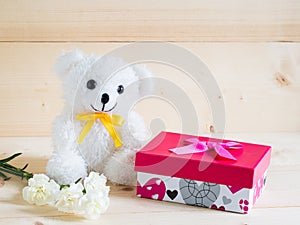 A beautiful gift with lovely bear and nice white carnation flower on wooden background