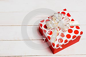 Beautiful gift packaging, red box with ribbon on white wooden background