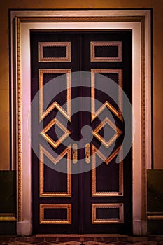 Beautiful gilded door, baroque style, in a gloomy mysterious corridor