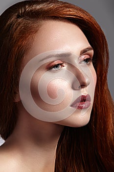 Beautiful ginger young woman with luxury hair style and fashion gloss makeup. Beauty closeup model with red hair