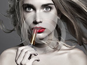 Beautiful girl Applying lipstick. young Woman putting red lipstick