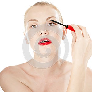 Beautiful girl applying mascara on her eyelashes.