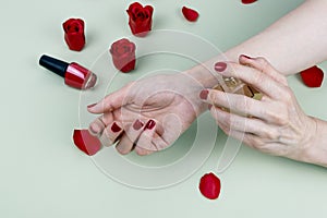 Beautiful girl applying perfume on her wrist. Roses and nail polish