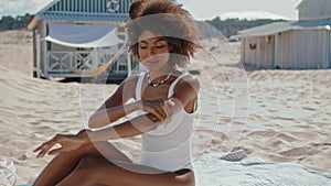 Beautiful girl applying suntan lotion on beach. Stylish woman sunbathing alone