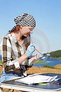Beautiful girl archaeologist carefully clears the find with a brush