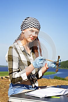 Beautiful girl archaeologist carefully clears the find with a brush