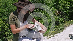 Beautiful girl archaeologist inspects the skull of a domestic sheep or goat near the settlements of ancient people.