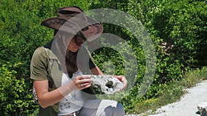 Beautiful girl archaeologist inspects the skull of a domestic sheep or goat near the settlements of ancient people.