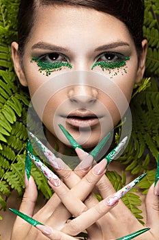 Beautiful girl with art make-up, fern leaves and long nails. Manicure design. The beauty of the face.