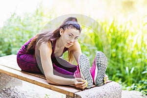 A beautiful girl athlete performs an exercise on a bench in the park in a warm summer morning. Concept on healthy lifestyles