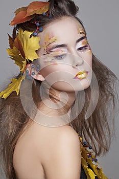 Beautiful girl with autumn make up and leaves on head