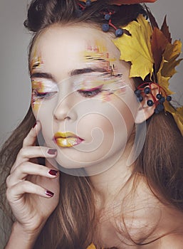 Beautiful girl with autumn make up and leaves on head